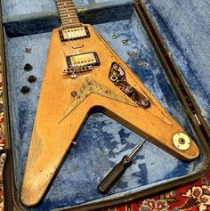 an old wooden guitar sitting in a case on top of a blue carpeted floor