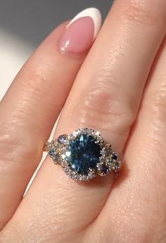 a close up of a person's hand with a ring on their finger and an oval shaped blue stone in the middle