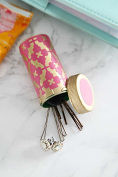 a pink and gold canister sitting on top of a table next to other items