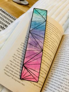 a bookmark made out of colored paper sitting on top of an open book