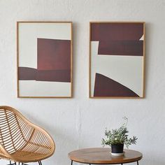 two paintings hang on the wall next to a chair and table