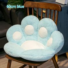 a chair with a blue flower shaped pillow on it's back and two white balls in the center