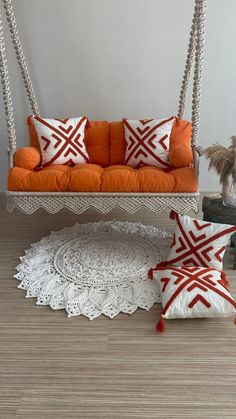 an orange and white couch sitting on top of a wooden floor next to two pillows