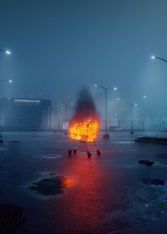 a person pushing a shopping cart on a wet parking lot in the rain at night