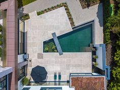 an aerial view of a house with pool and umbrellas in the foreground, surrounded by greenery