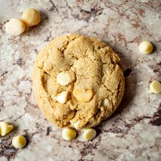 a close up of a cookie with white chocolate chips around it on a marble surface