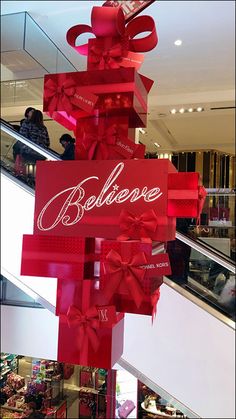 a large red sign that says believe and has bows on it