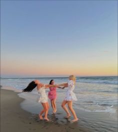 three young women are playing on the beach