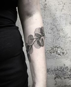 a woman's arm with a leaf tattoo on it