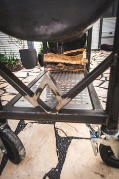 the back end of an outdoor grill on a patio with potted plants in the background