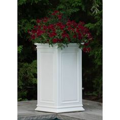 a white planter with red flowers in it