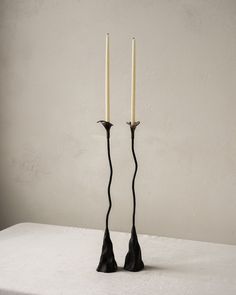 two candles sitting on top of a table next to each other with black sticks sticking out of them