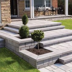 an outdoor patio with steps leading up to the front door and small tree in the middle