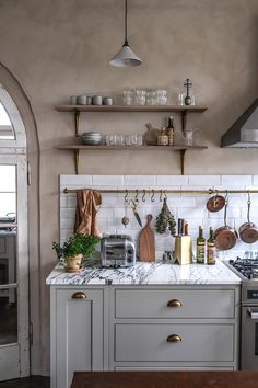 a kitchen with marble counter tops and open shelving above the stove, along with hanging pots and pans