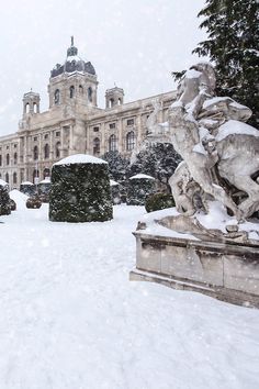 a large building that has some statues in front of it and snow falling on the ground