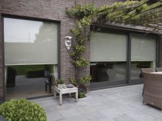 an outdoor patio area with chairs, table and plants on the side of the building