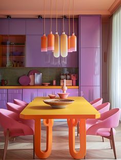 a dining room table with pink chairs and orange lights hanging from it's ceiling