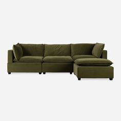 a green sectional couch and ottoman with pillows on the bottom, in front of a white background