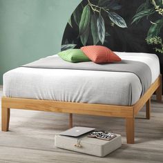 a bed with two pillows on top of it next to a green wall and wooden floor