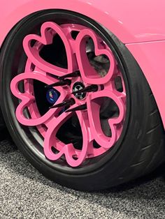 a pink car with hearts painted on it's front wheel rims and tires