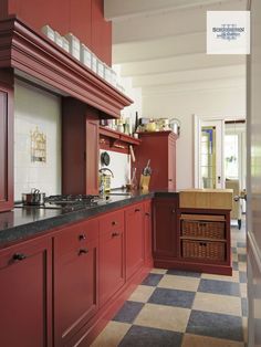 a kitchen with red cabinets and checkered flooring