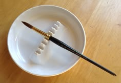 a white bowl with two brushes in it