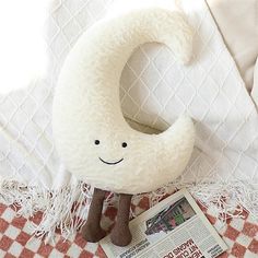 a white stuffed animal sitting on top of a bed next to a magazine and pillow