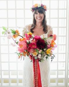 a woman holding a bouquet of flowers in front of a window with an orange ribbon