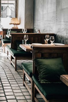 empty tables in a restaurant with green cushions and wine glasses on the backrests