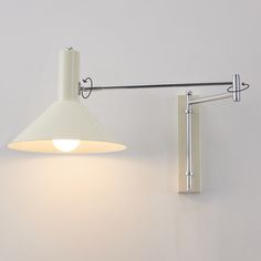 a white wall mounted light on the side of a wall next to a lamp shade