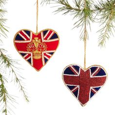 two british flags shaped like hearts hanging from a christmas tree with pine branches in the foreground