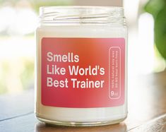 a candle that is sitting on a table with the words smells like world's best trainer