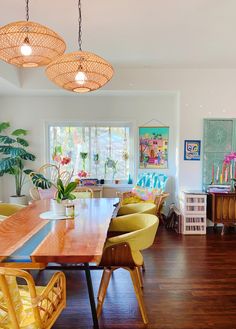 a dining room table with yellow chairs and hanging lights in the middle of the room