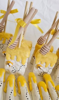 yellow and white desserts with wooden sticks sticking out of them, all decorated in different designs