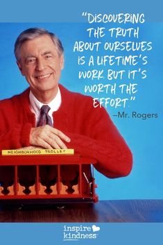 a man in a red sweater and tie holding a toy train with words above it