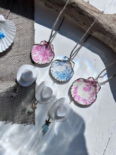 four necklaces with different designs on them sitting next to a piece of driftwood