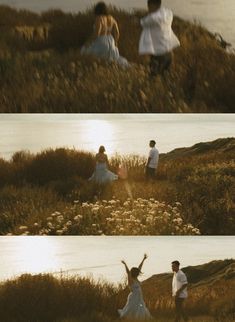 two people standing on top of a grass covered hillside next to water and flowers in the foreground