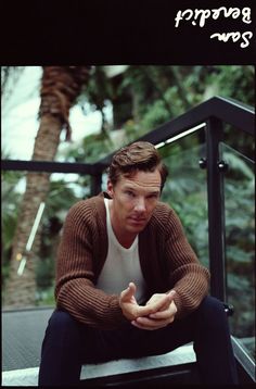 a man sitting on top of a stair case next to trees and palm trees in the background