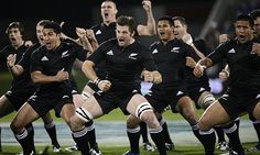 a group of rugby players are running on the field with their arms in the air