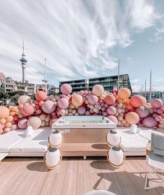 an outdoor area with couches, tables and balloons on the wall behind it in front of a cityscape