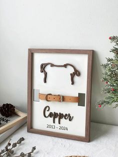 a wooden frame with a horse shoe and name on it next to a christmas tree