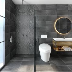 a modern bathroom with grey tiles and a round mirror on the wall above the toilet