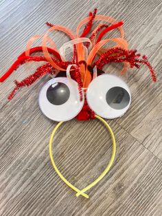 a pair of googly eyes with orange streamers on top of the headband