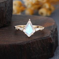 a ring with an opal stone in the center on top of a wooden stump