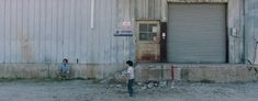 two young boys standing in front of an industrial building