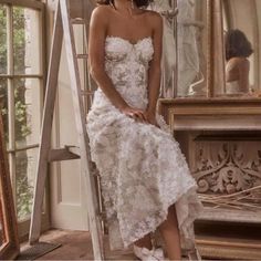 a woman in a white dress sitting on a step ladder