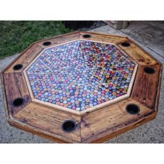 a wooden table with many different colored buttons on it's top and two holes in the middle