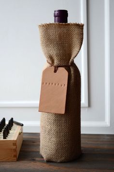 a wine bottle wrapped in burlap with a tag attached to it and some brushes on the floor