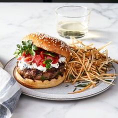 a burger and french fries on a plate with a glass of water in the background