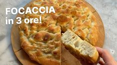 a person holding a piece of bread on top of a cutting board with the words focaccia in 3 ore